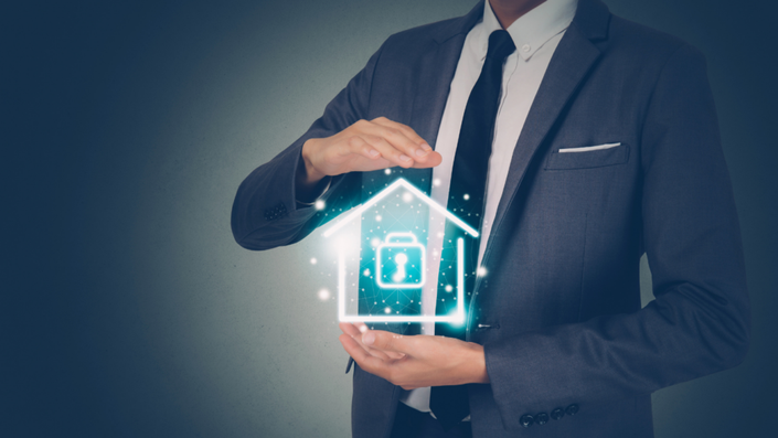 Hombre de traje con una casa digital en la mano que representa la seguridad.