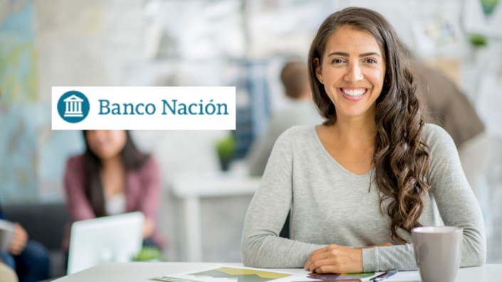 Mujer sentada en su oficina trabajando en su computadora y sonriendo