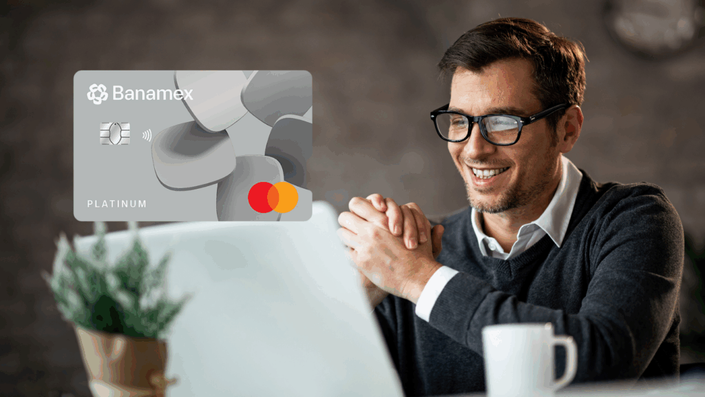 Hombre trabajando en su laptop y sonriendo, con una tarjeta de crédito Banamex Platinum destacada en la imagen.