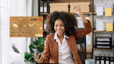 Mujer sonriente usando teléfono celular y tarjeta ICBC Visa Gold