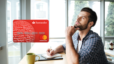 hombre con un cuaderno mirando hacia arriba y pensando con tarjeta de crédito Santander Visa Internacional en el lateral