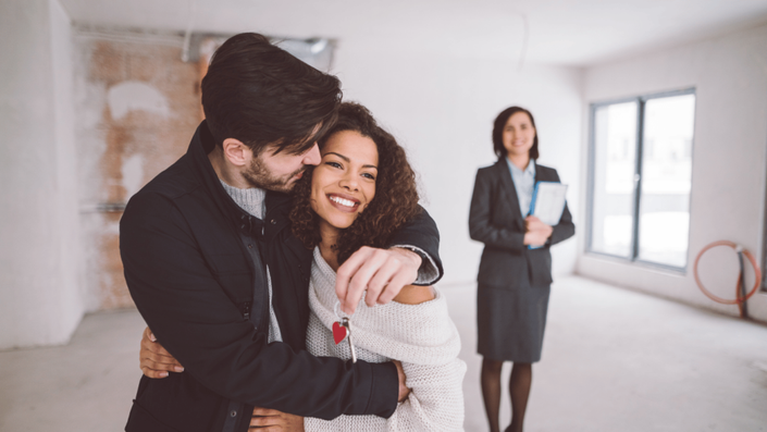 Pareja feliz recibiendo las llaves de su nueva vivienda, simbolizando el éxito al comprar casa en México con el apoyo de una agente inmobiliaria.