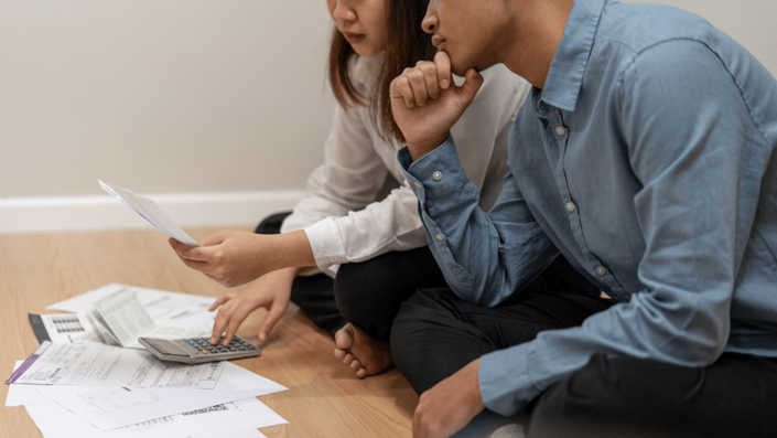 Pareja revisando su estado de cuenta con una calculadora y notas sobre pagos mensuales de un crédito personal.