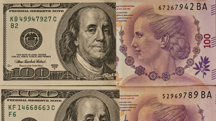 Billetes de 100 dólares estadounidenses junto a un billete de 100 pesos argentinos, representando la diferencia entre el dólar Mep y otras opciones de cambio en Argentina.