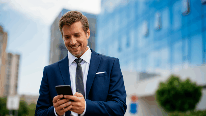 Hombre de negocios mirando su teléfono móvil en una ciudad, usando una aplicación bancaria para consultar el CBU en Argentina.