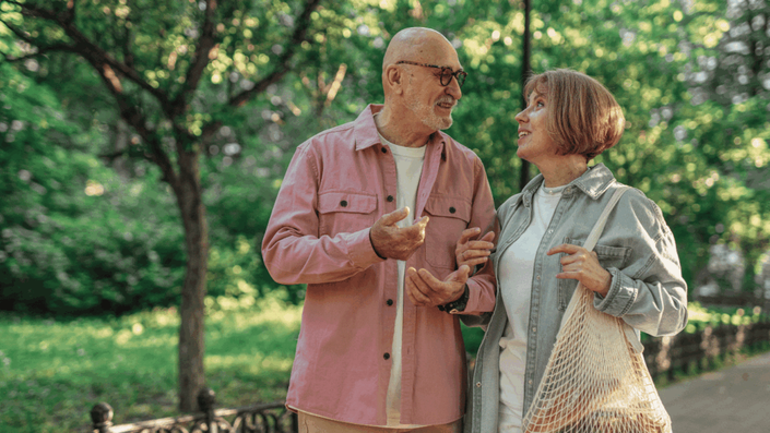 Pareja de adultos mayores caminando por un parque, disfrutando de su tiempo juntos mientras reflexionan sobre la jubilación mínima en Argentina y la importancia de la planificación financiera.