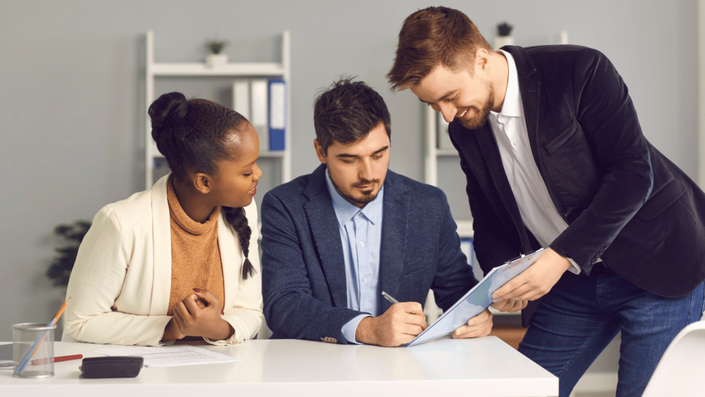 Personas firmando un contrato de préstamo con mal historial crediticio, revisando términos y condiciones en una oficina financiera.