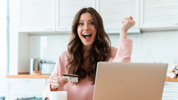 Mujer sonriente mostrando su tarjeta de crédito, aprendiendo sobre qué es el CAT y cómo influye en sus finanzas.