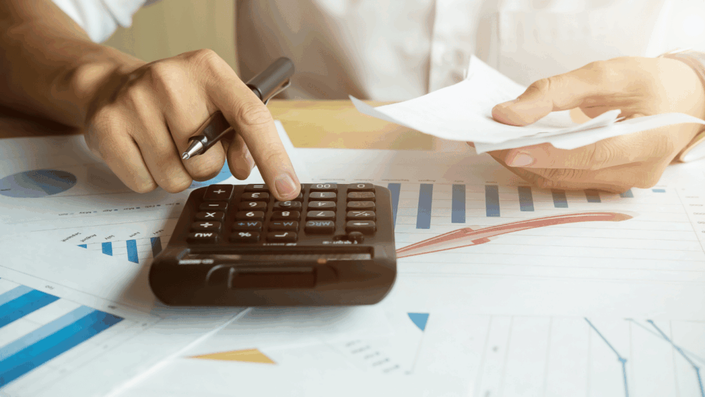 Una persona calculando números con una calculadora, trabajando en una hoja con gráficos y datos relacionados con las tandas en México